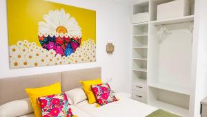 a bedroom with a yellow accent wall and a couch with pillows at Apartamentos La CárcaVa in Carcaboso