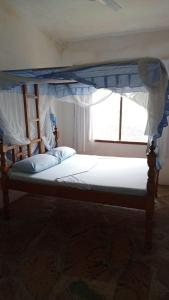 Un dormitorio con una cama con dosel y una ventana. en Watamu villas, en Watamu 4 fotos más