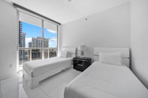 two beds in a white room with a large window at W Miami - LUXURY condo Amazing Views in Miami +30 photos