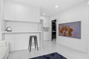 a kitchen with white cabinets and a stool in a room at QV Stays Viaduct Harbour Elegance in Auckland