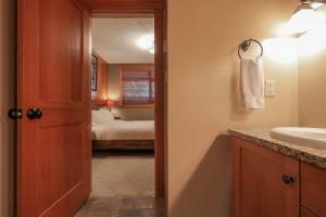 a bathroom with a sink and a bedroom with a bed at Slalom Creek 2 Bedroom & Den in Rossland