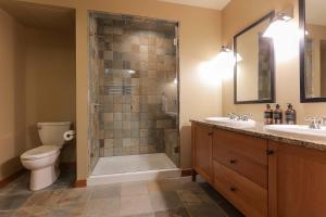 a bathroom with a shower and a toilet and two sinks at Slalom Creek 2 Bedroom & Den in Rossland +16 photos
