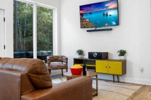 a living room with a couch and a tv on a wall at Modern Cabin Retreat Easy Drive to Canton and Tyler in Chandler