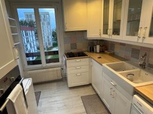 a kitchen with white cabinets and a sink at Appartement lumineux centre in Beauvais +10 photos