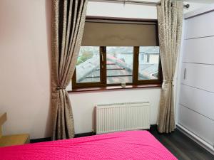 a bedroom with a pink bed and a window at Detached house in Newtown Mount Kennedy