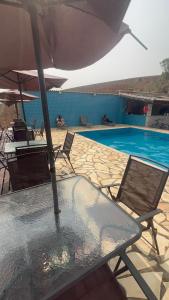 una mesa con sombrilla y sillas junto a la piscina en Sítio Lopes, en Toledo