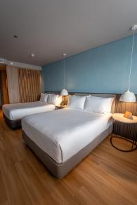 two beds in a hotel room with two lamps at Hotel Habitel Select in Bogotá