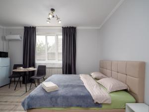 アルマトイにあるZhetysu Apartment on Sayahatのベッドとテーブルと窓のある寝室
