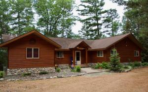 a log home with a porch and a yard at Fishtrap Lake Lodge 4400 sq feet 6 bedroom 3 bath in Boulder Junction