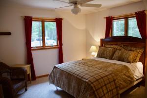 a bedroom with a bed with red curtains and windows at Fishtrap Lake Lodge 4400 sq feet 6 bedroom 3 bath in Boulder Junction