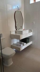 Un baño con un inodoro blanco y un espejo. en Casa Rosada temporada em Rio de Contas, en Rio de Contas