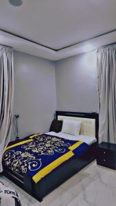 um quarto com uma cama com um cobertor azul e amarelo em A well-built 2 bedroom duplex em Lekki