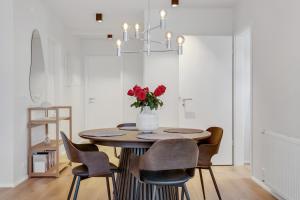 雷克雅未克Downtown Apartment with Parking的餐桌、椅子和插着红玫瑰的花瓶