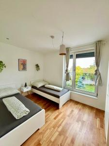 a bedroom with two beds and a large window at Spacious Modern Apartment with Free Parking in Gerasdorf bei Wien +6 photos