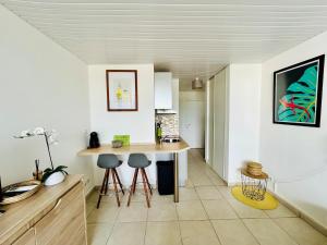 a kitchen with a table and stools in a room at Soleilcaraïbe Studio - direct beach access Gosier in Le Gosier