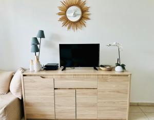 a tv on top of a wooden dresser in a living room at Soleilcaraïbe Studio - direct beach access Gosier in Le Gosier