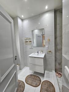 a white bathroom with a sink and a mirror at Appartement Casa in Essaouira
