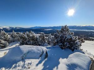 a snow covered mountain with trees and the sun in the sky at Le CerfBlanc in Les Angles