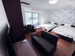 Zimmer mit 2 Betten, einem Sofa und einem TV in der Unterkunft SA Inn Nagano Nakagosho - Vacation STAY 45417v in Nagano