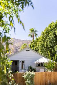 a white house with a palm tree behind a fence at Casa Cody in Palm Springs