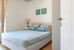 a white bedroom with a bed with blue pillows at Sea & Stone Villas in Koundouros