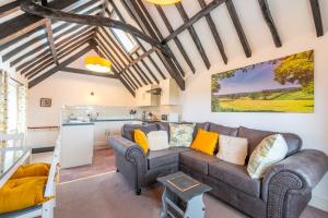 een woonkamer met een bank en een keuken bij Valley Farm Holiday Cottages in Axminster