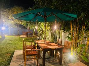 uma mesa de madeira com um guarda-sol verde em um jardim em Sun and Moon spa em Tangalle