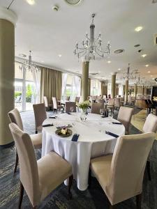 a dining room with a white table and chairs at Hotel Woiński Spa in Lubniewice