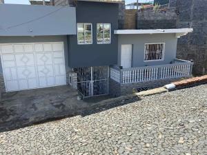 a house with white garage doors and a stone driveway at MONTROND House in São Filipe