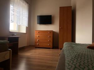 a bedroom with a bed and a dresser with a television at Piątka noclegi- Łódź in Łódź