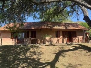 a house with a tree in front of it at Cabañas Casa Raiz VGB in Villa General Belgrano
