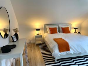 a bedroom with a white bed with orange pillows and a mirror at Urlaub in der Eifel am Rursee - Wita31 in Einruhr
