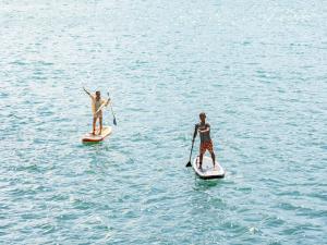 two people are standing on paddle boards in the water at Kaamlanai Harbor - Vacation STAY 48860v in Nichinan