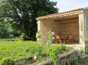 Bassac的住宿－Le Moulin de Bassac，一座石头建筑,在院子里配有桌椅