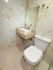 a bathroom with a white toilet and a sink at Hotel Ideal 5 in Araguaína