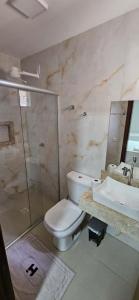 a bathroom with a toilet and a shower and a sink at Hotel Ideal 5 in Araguaína