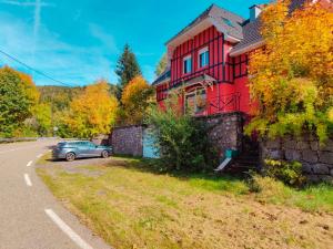 Un coche aparcado junto a una casa roja al costado de una carretera. en Mountain Getaway - Nordic Hot Tub, Warmth & Nature, en Bussang