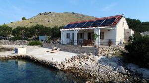 a house with solar panels on its roof next to the water at House Lateen in Vala