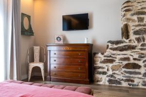 a bedroom with a dresser and a tv on a stone wall at A Casa da Fonte Azul in Ourense