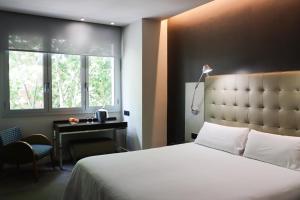 ein Schlafzimmer mit Bett, Schreibtisch und Fenster in der Unterkunft Hotel Urpí in Sabadell + 17 Fotos