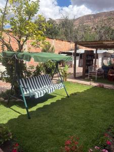 Una sombrilla verde y un banco en un patio. en hostel arcoiris urubamba, en Urubamba 19 fotos más