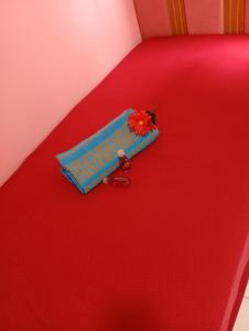 een blauwe tas met een bloem op een rood bed bij Doce lar in Montes Claros