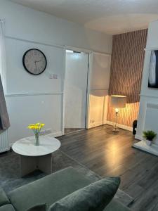 a living room with a table and a clock on the wall at Tyne Relaxation in Newcastle upon Tyne