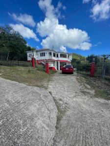 une maison avec une voiture rouge garée devant dans l'établissement Spacious 4-Bedroom Island Home Near Jolly Harbour Beaches, à Bolans