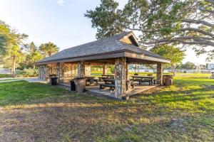 a wooden pavilion with benches and picnic tables in a park at Near Beach! Modern Ground-Floor Condo in St Pete in St Pete Beach