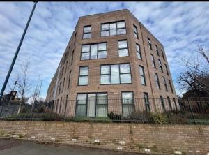 a tall brick building with windows on a fence at Near Old Trafford & Media City 2BR Flat in Manchester