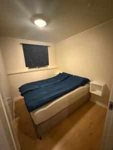 een kleine slaapkamer met een bed met een blauwe deken bij Tromsø Stay in Tromsø