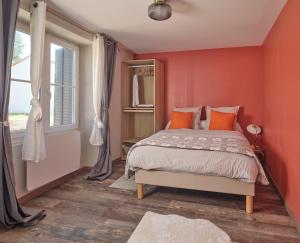 Un dormitorio con paredes rojas y una cama con almohadas naranjas. en La Résidence AKWABA, en Saint-Philbert-de-Grand-Lieu
