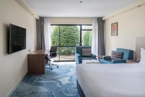 オークランドにあるホリデイ イン オークランド エアポートのベッドと机と椅子があるホテルの部屋