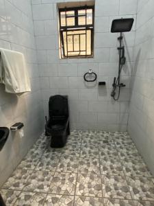 La salle de bains est pourvue de toilettes noires et d'une fenêtre. dans l'établissement KIGALI AIRPORT TRANSIT RESIDENCe, à Kigali